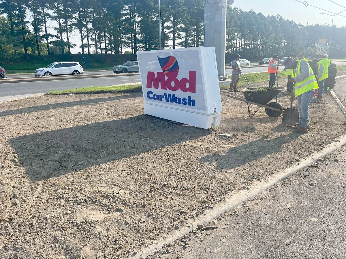 A car wash sign is sitting on the side of the road