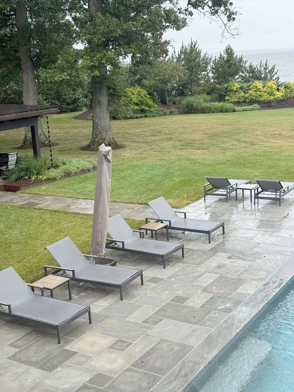 A row of lounge chairs are lined up next to a swimming pool