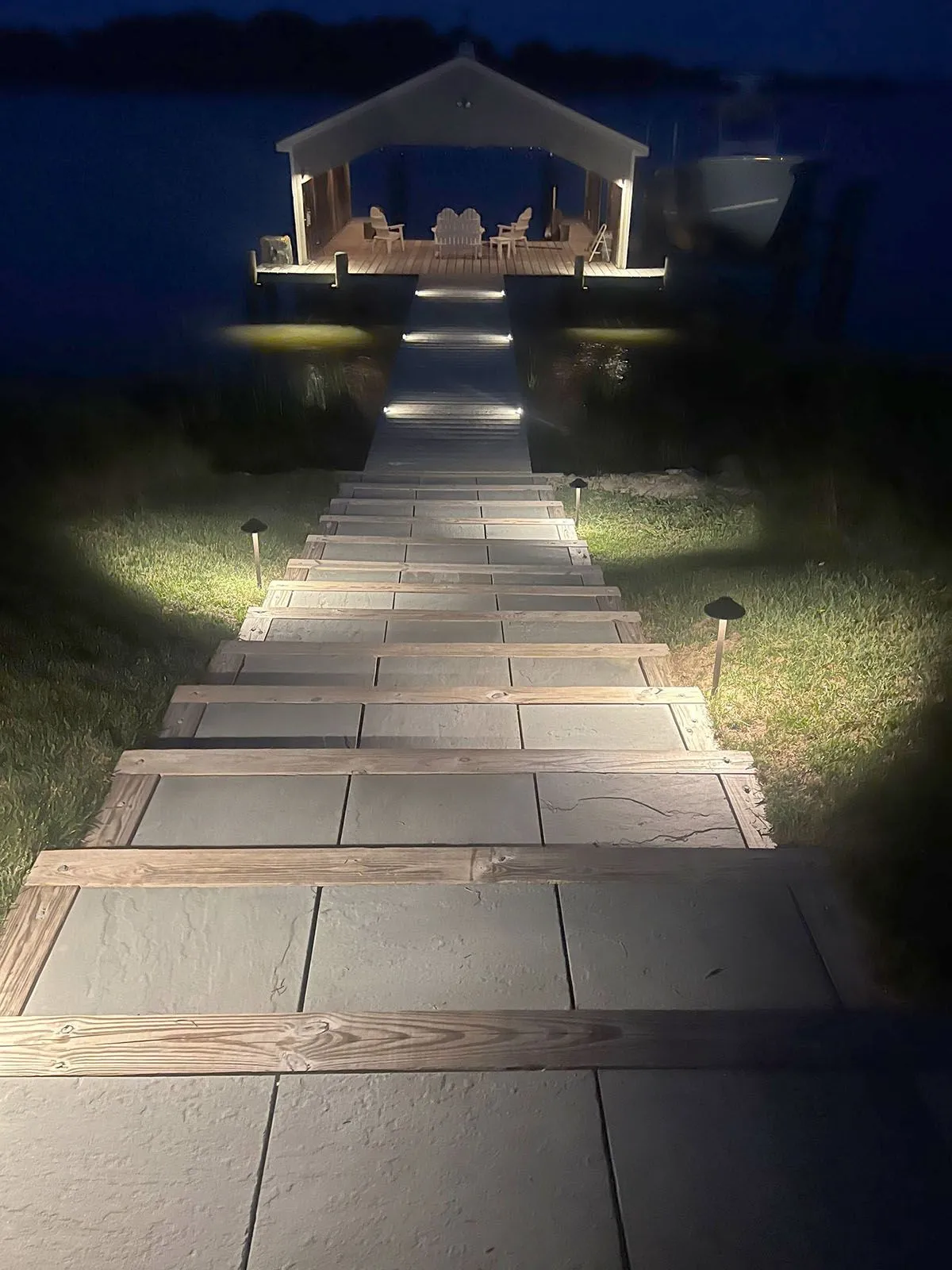 A well-lighted staircase leading to a gazebo overlooking a body of water at night